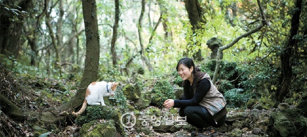 Lee Ji-young and her cat, Nabi, sit together in the Fantasy Forest of Gotjawal Park on Jeju Island. The two often guide the way together. [KWON HYuK-JAE] 