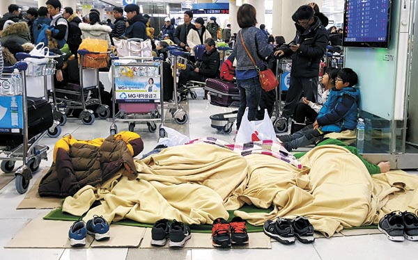 Passengers camp on the floors of the Jeju International Airport early Sunday, waiting for airlines to resume flights out. A flight ban was extended to early Monday after the weather conditions got worse. [NEWSIS] 