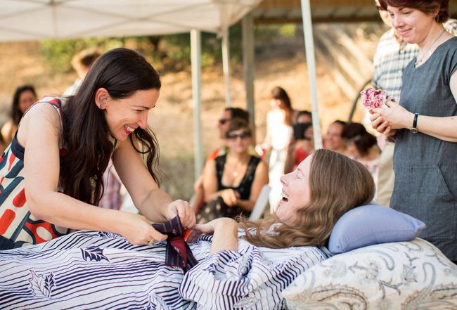 Amanda Friedland, left, surrounded by friends and family adjusts her friend Betsy Davis's sash as she lays on a bed during her "Right To Die Party" in Ojai, Calif. [AP] 