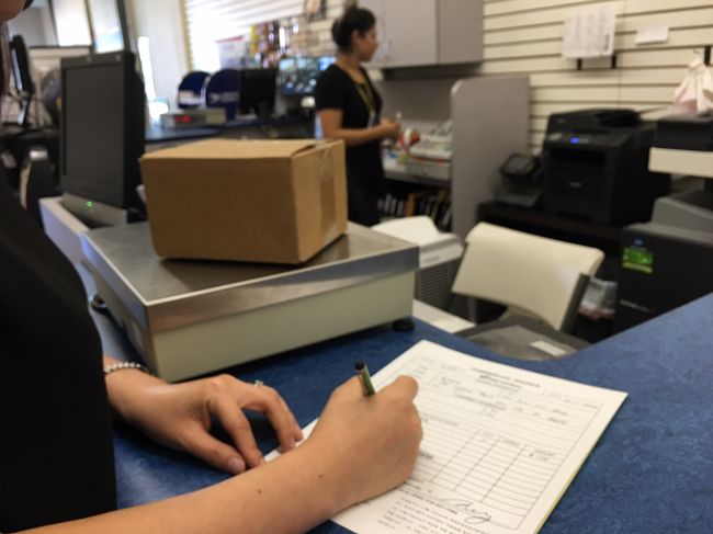 Shipping businesses in L.A. Koreatown are fighting for survival. A customer at one of the shipping companies in town is filling out a form to send a package to South Korea.