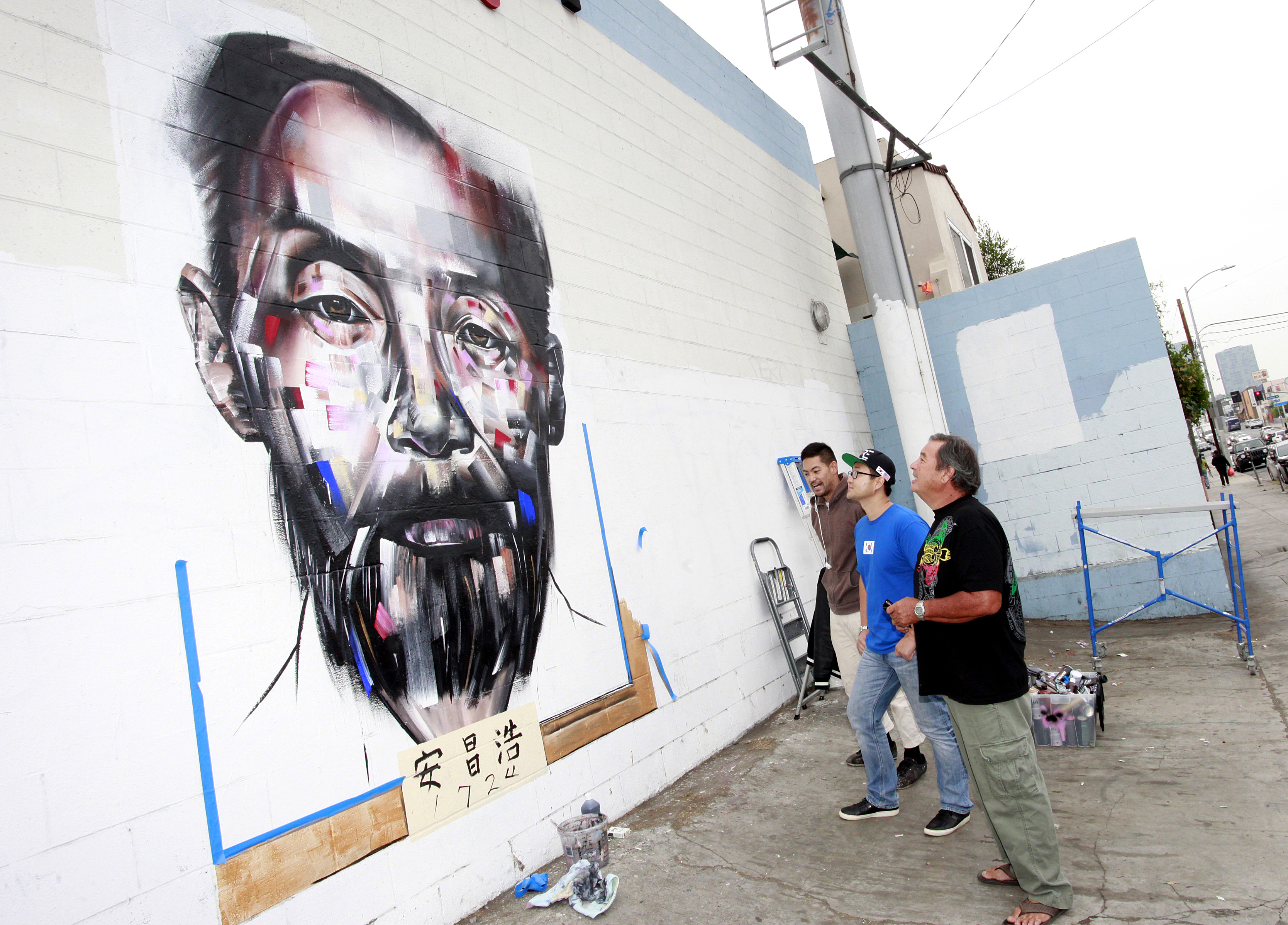 Mural artist Joseph Lee, KORE CEO Matthew Kim, and Ahn Chang-ho's grandson Phillip Ahn Cuddy, are staring at the portrait of Dosan