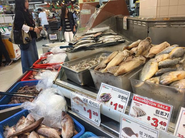 The supply of imported agro-fishery foods from South Korea is expected to exceed a total cost of $1 billion this year. A customer is tasting kimchi at a Korean market. 