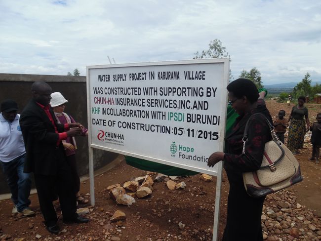 Public servants and local residents in Karurama, Burundi is putting up a sign to notify construction of the water supply system in May of last year. Chun-Ha Insurance Services has been helping them annually through a paid raffle contest. 