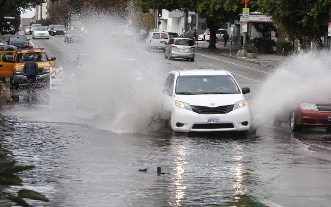 Rough weather in L.A. is increasing potholes around the city. Cars are being driven over a pothole on the busy Wilshire Boulevard. Sang Jin Kim