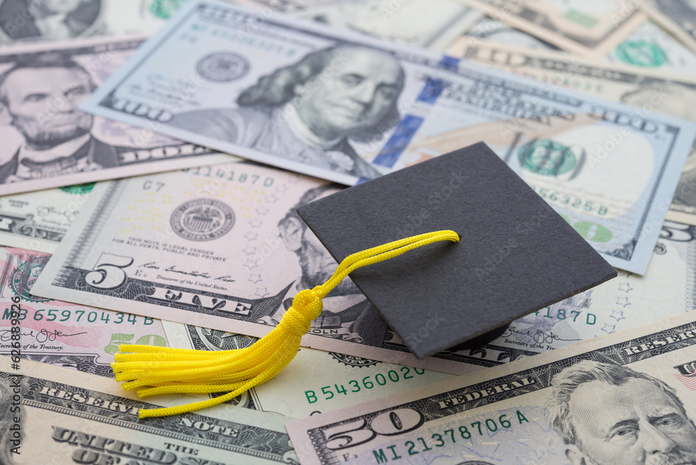 Graduation cap resting on U.S. dollar bills representing 529 college savings plan benefits
