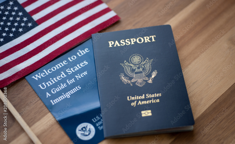 Passport of USA (United states of America) next to a Guide for new Immigrants - Welcome to the United states and American Flag. Wooden Background.