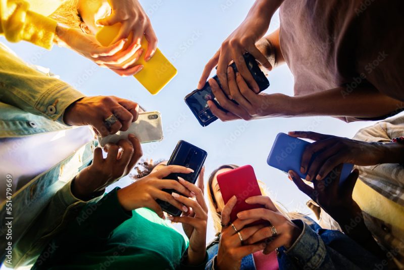 Young group of teenage student people using smart mobile phone outdoors