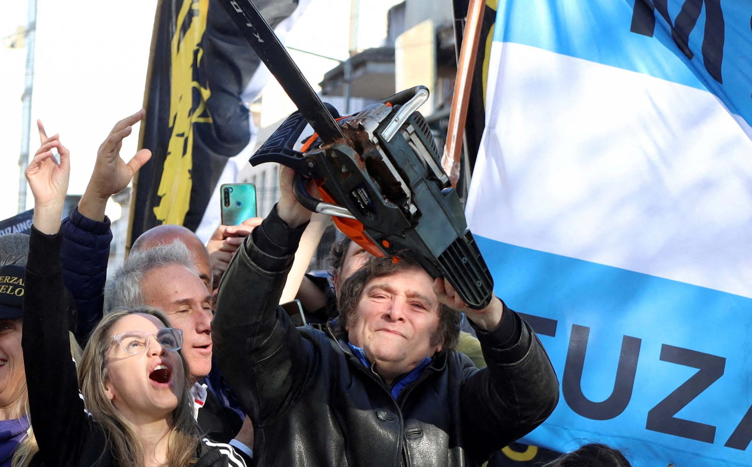 Javier Milei raises a chainsaw during a 2023 campaign rally in Argentina, symbolizing libertarian reforms