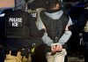 Trump Sets New Deportation Record as 527,000 Undocumented Removed in 9 Months ICE agents arresting a person during an immigration raid, with officers in vests on each side