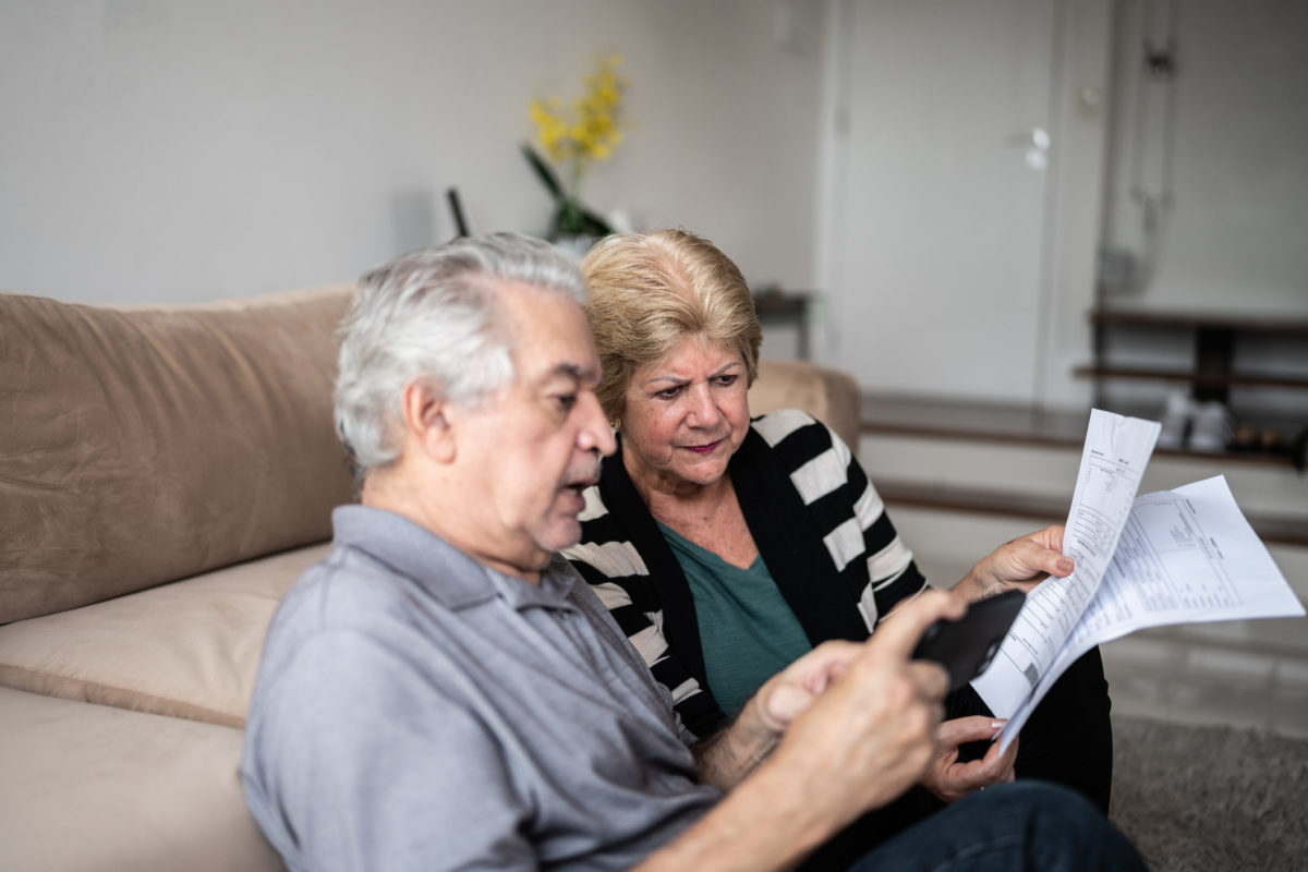 Senior couple checking medical bills on smartphone amid Medicare fraud settlement news