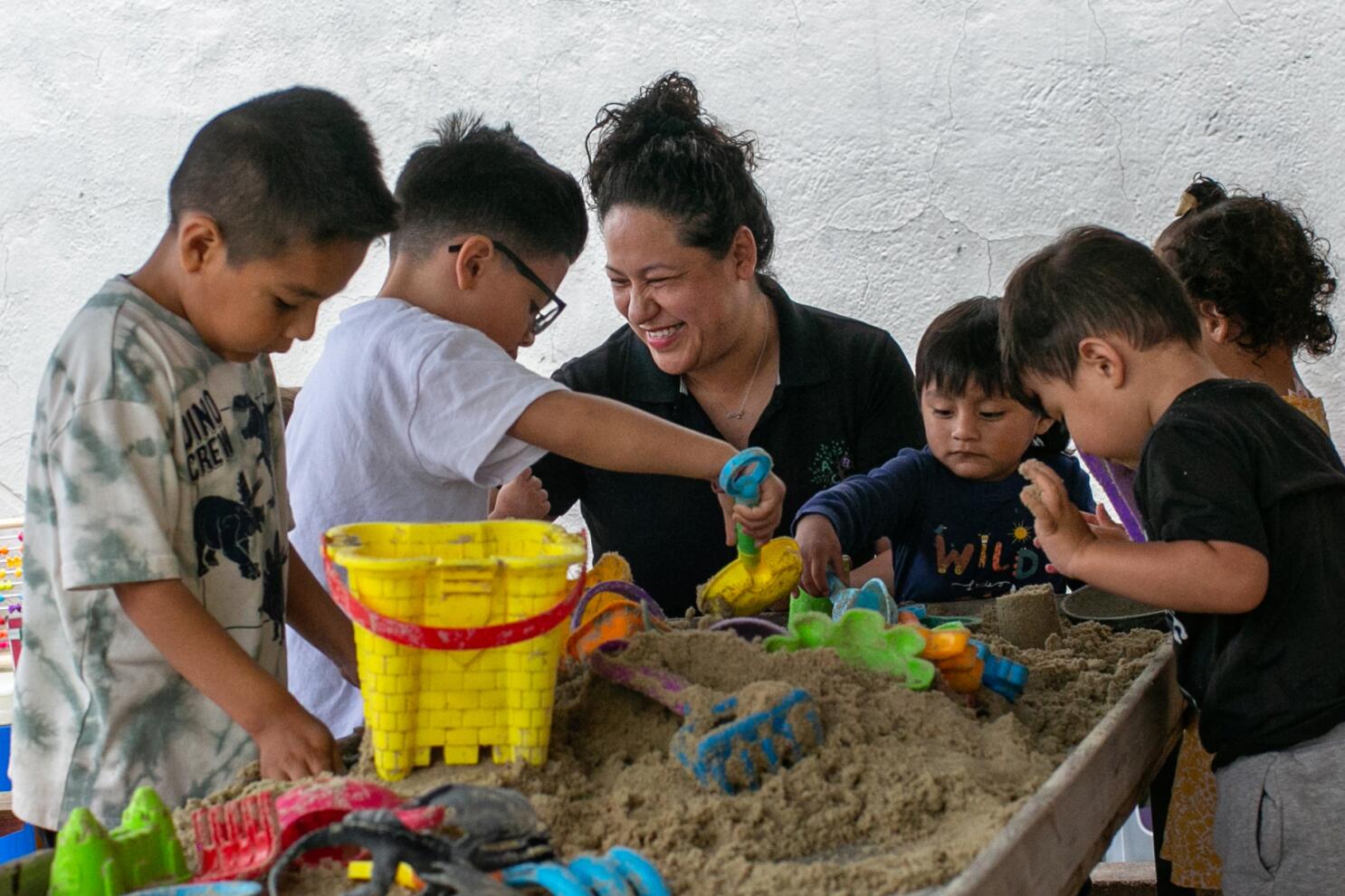 Adriana Lorenzo watches children play in a sandbox at her Boyle Heights day care during a warm May afternoon, highlighting LA public preschool conditions.