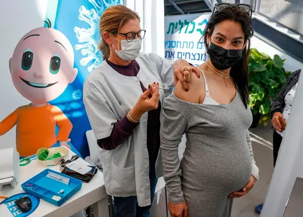 Healthcare worker prepares to administer COVID-19 vaccine to a pregnant woman