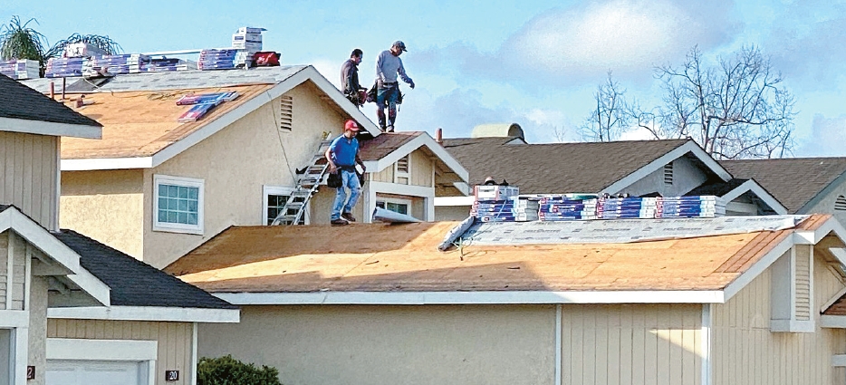Workers are on the roof to repair a home in Irvine related to California homeownership costs article