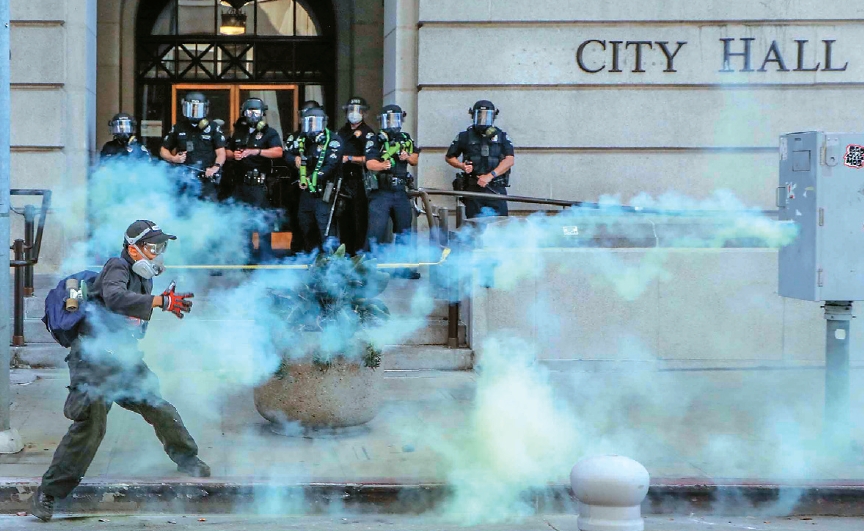 Protester throws tear gas canister back at police during No Kings protest in downtown Los Angeles