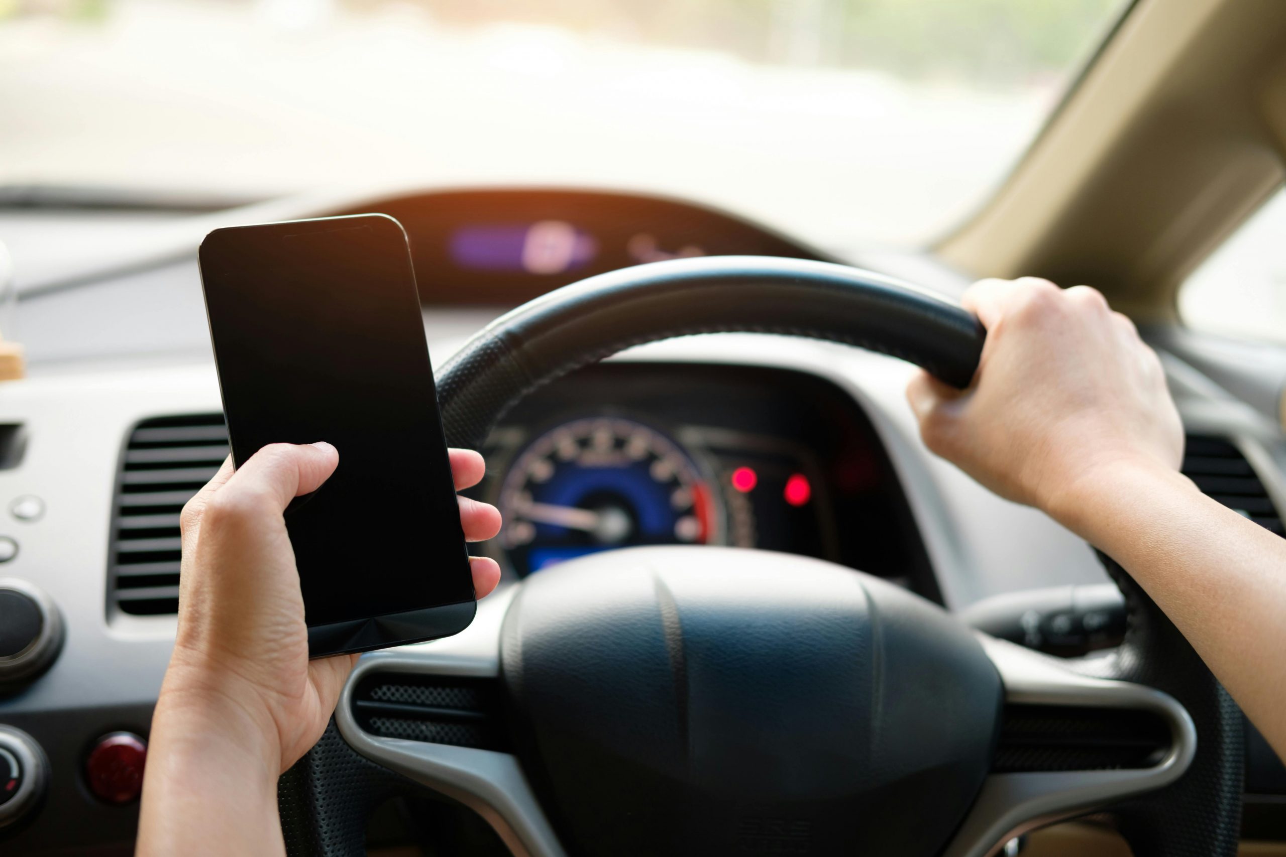 person holding phone while driving, violating California driving phone law