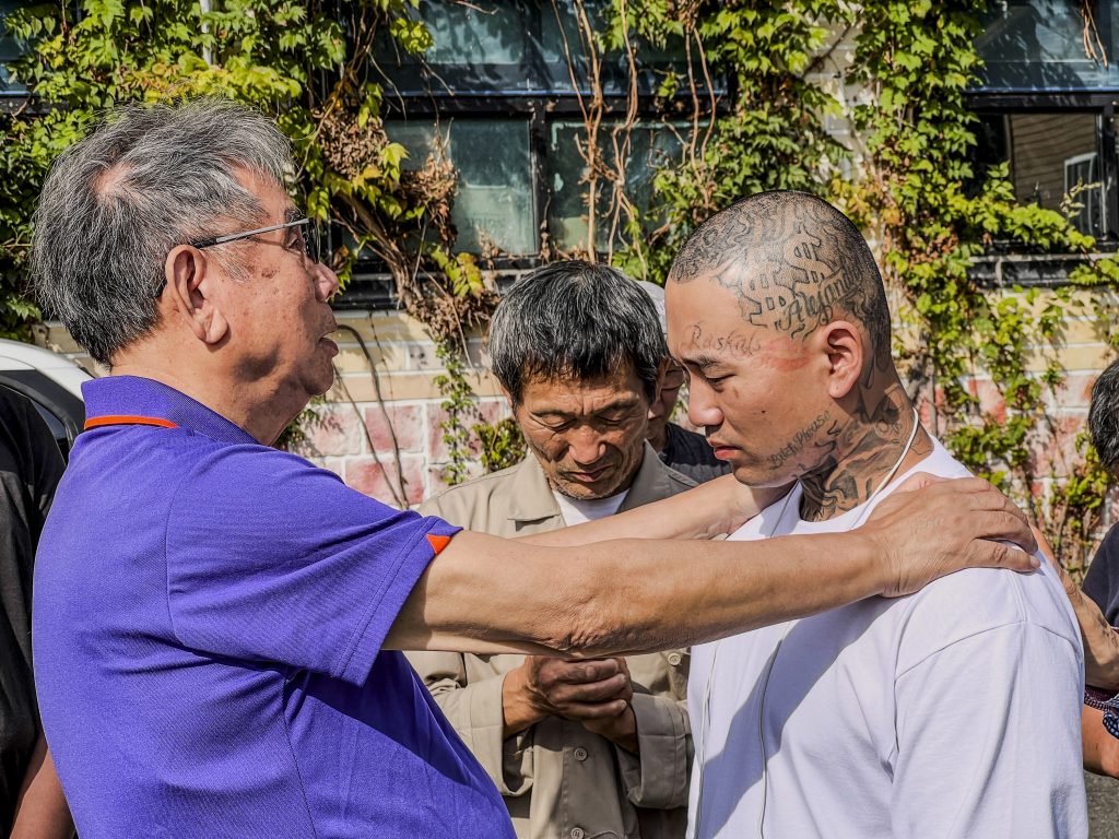 Pastor Ahn Il-kwon and shelter residents pray for K.Y. before military enlistment