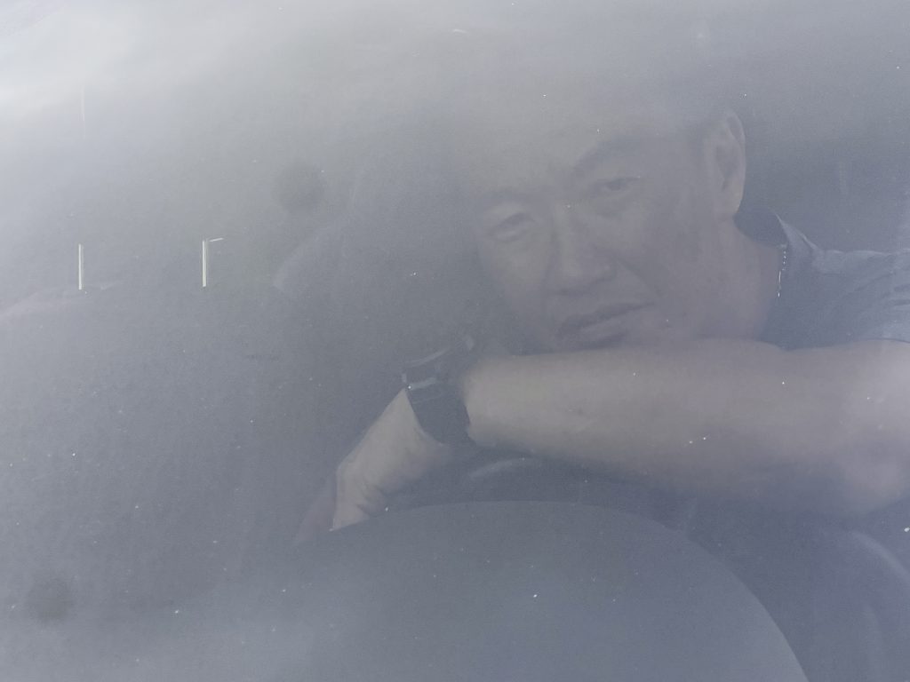 J.K. sitting in a car after deportation to South Korea