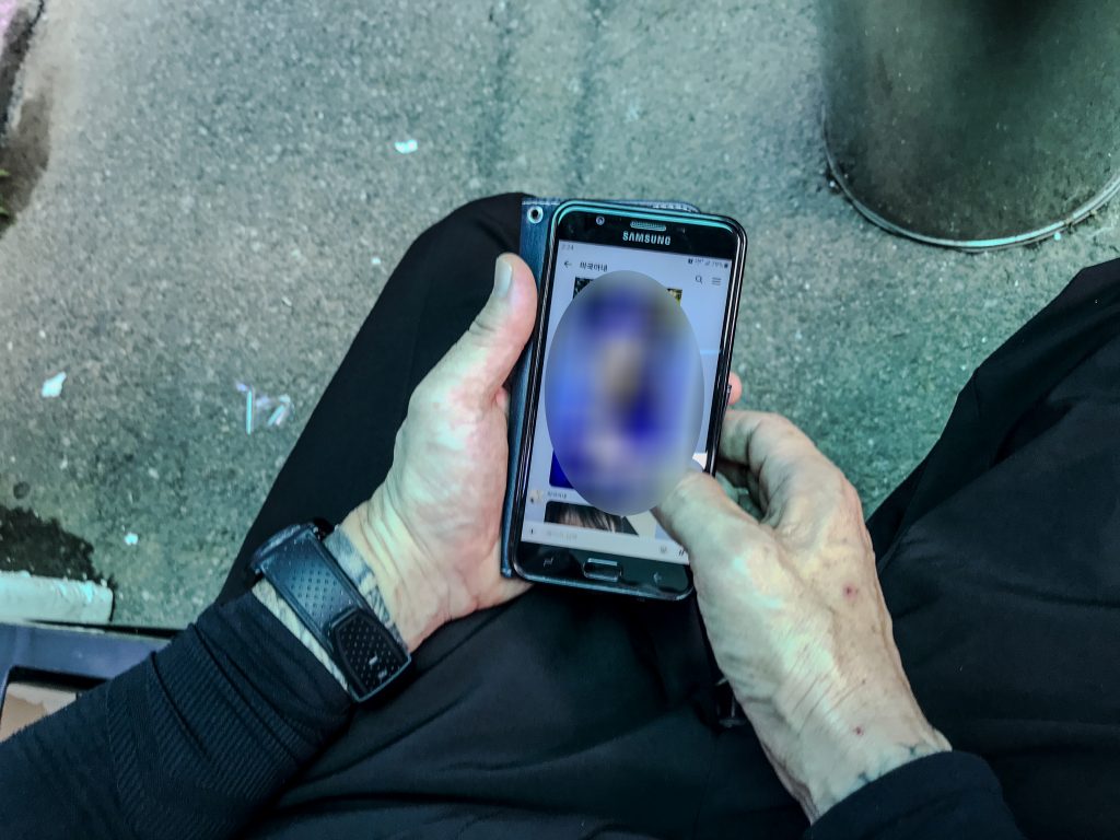 S.J. checks his phone to call his son in the United States