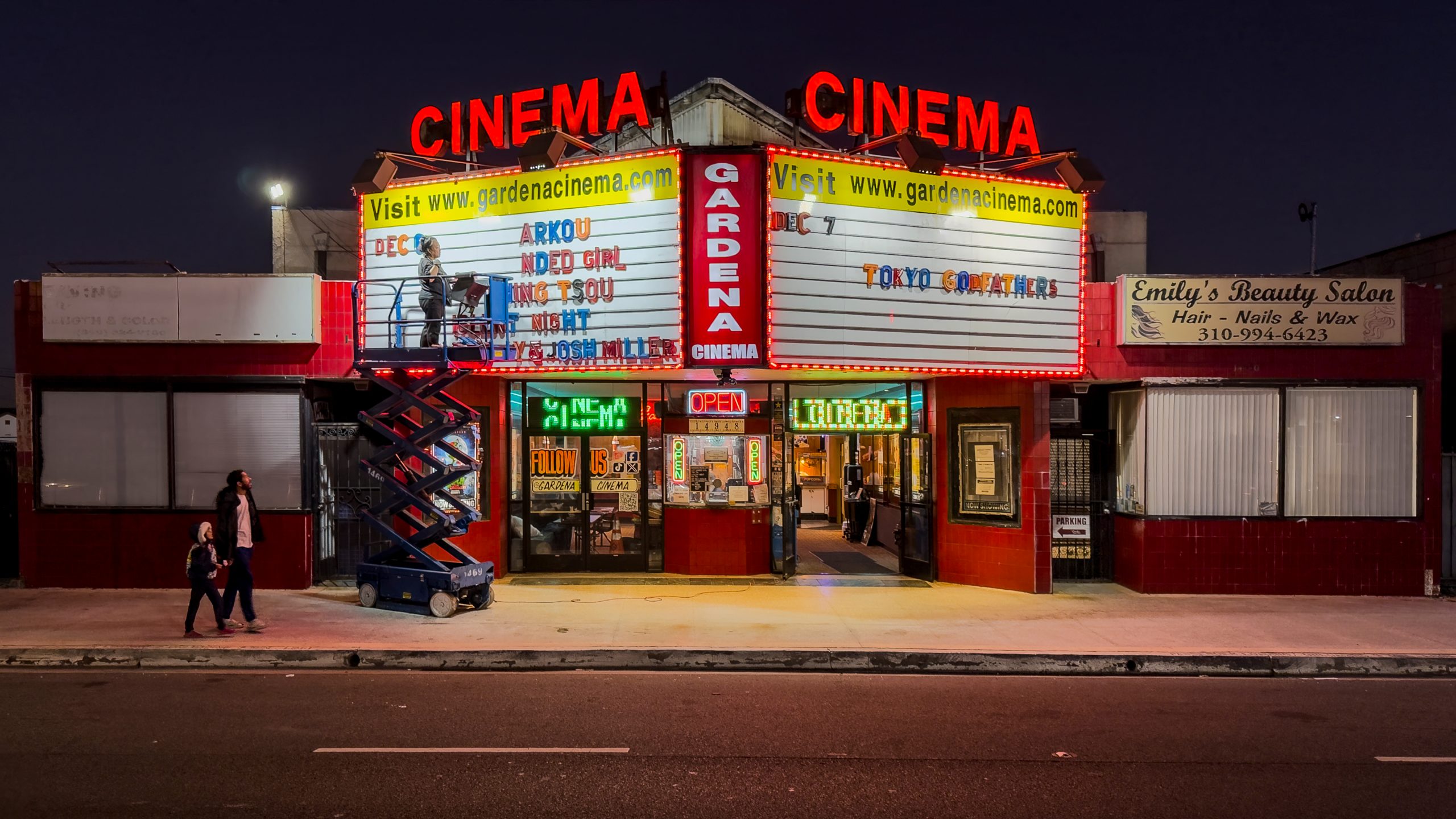 Judy Kim replacing marquee letters at Gardena Cinema entrance at night